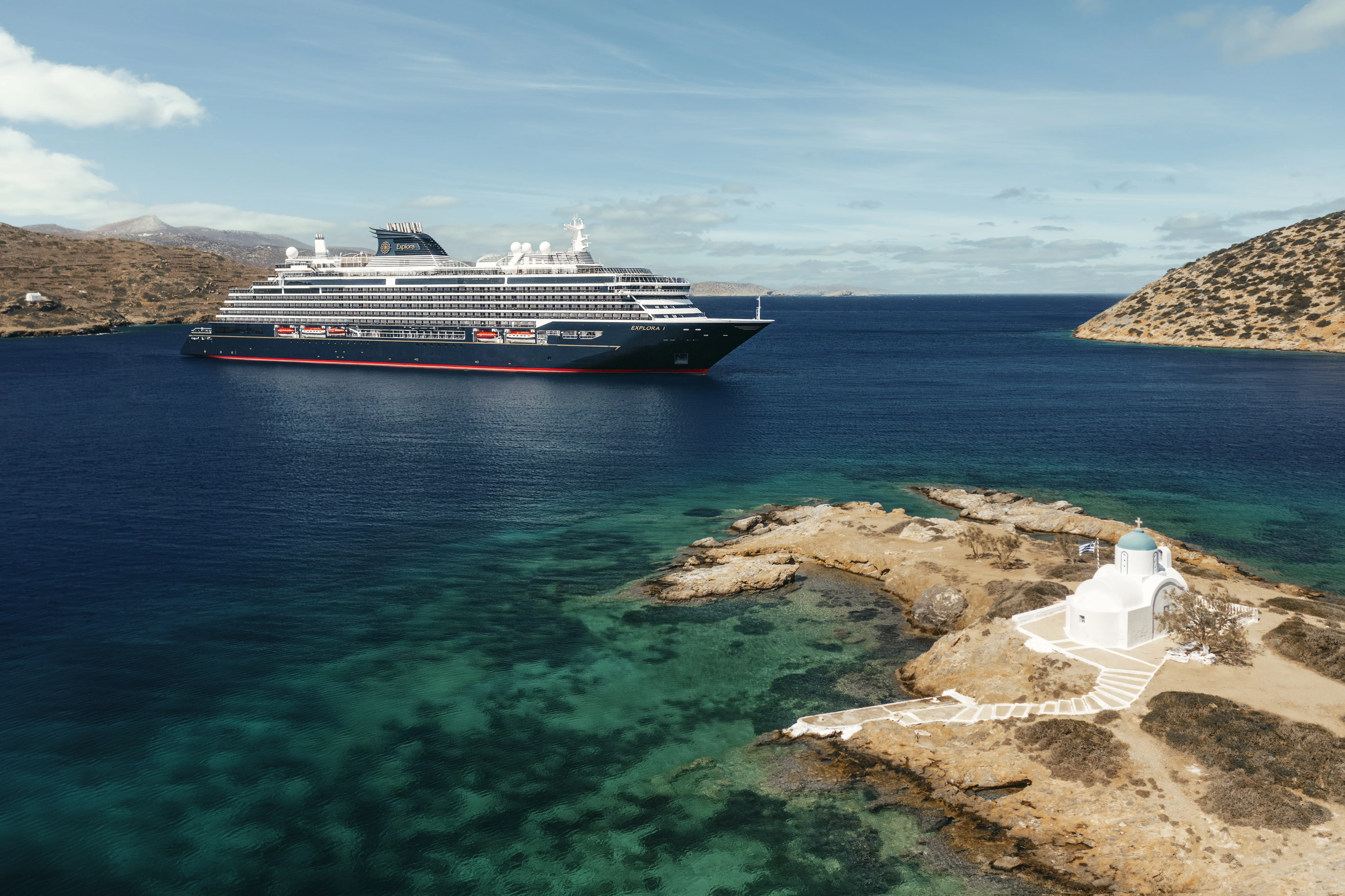 EXPLORA II anchored off a Greek island with a chapel in the foreground